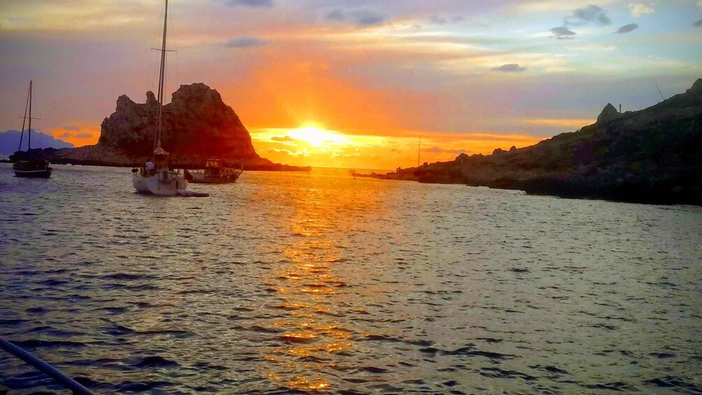 A sunset over a body of water with boats and rocky outcrops. 3