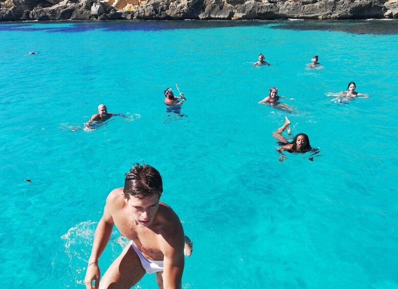 People swimming in a clear blue pool surrounded by rocky cliffs. 2