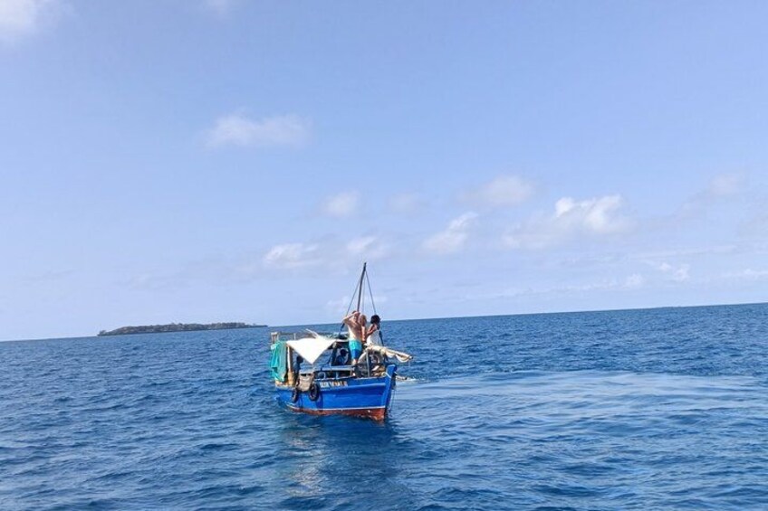 A blue boat on calm blue water with a clear sky and a distant landmass. 3