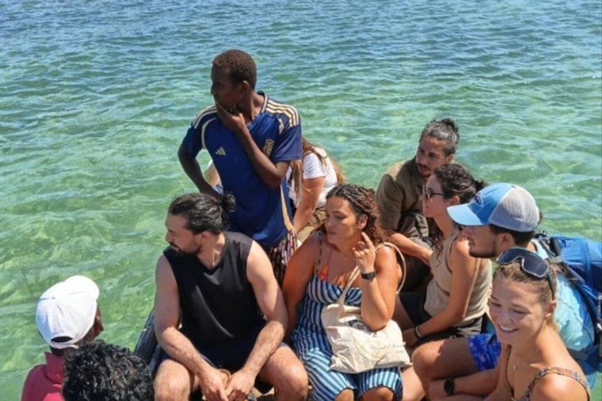 A group of people sitting on a boat in clear water. 3