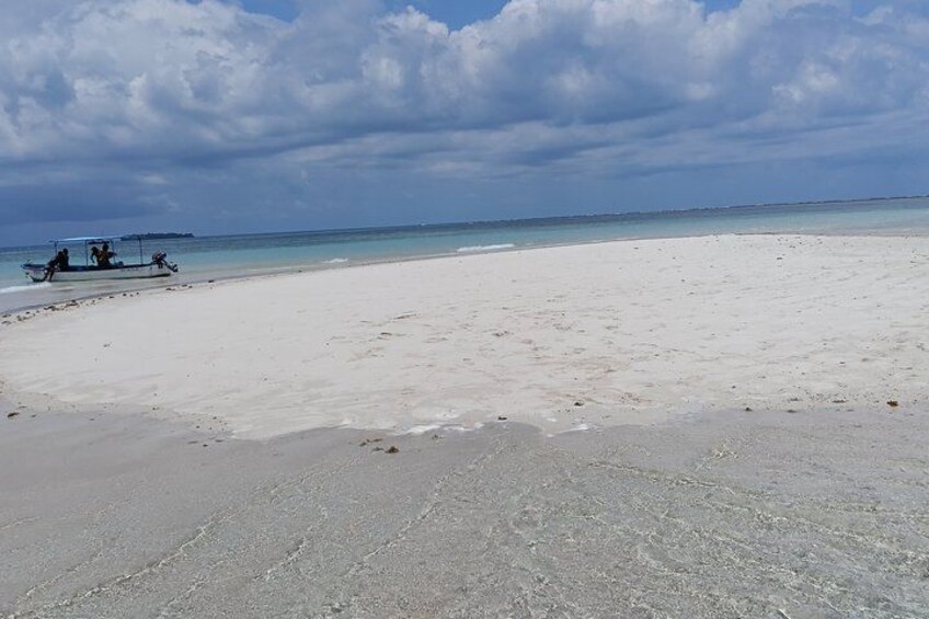 En strand med hvidt sand og en båd i det fjerne. 2