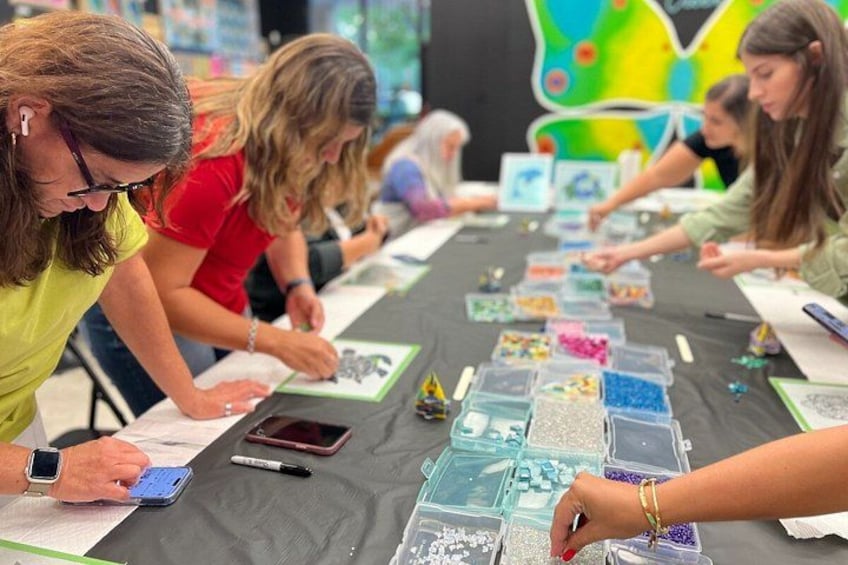 People engaged in a craft activity at a table with various materials. 3