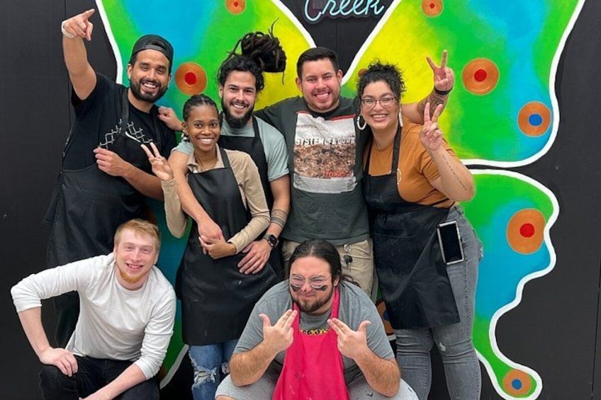 A group of people posing in front of a colorful wall with a design resembling a fruit or vegetable. 2