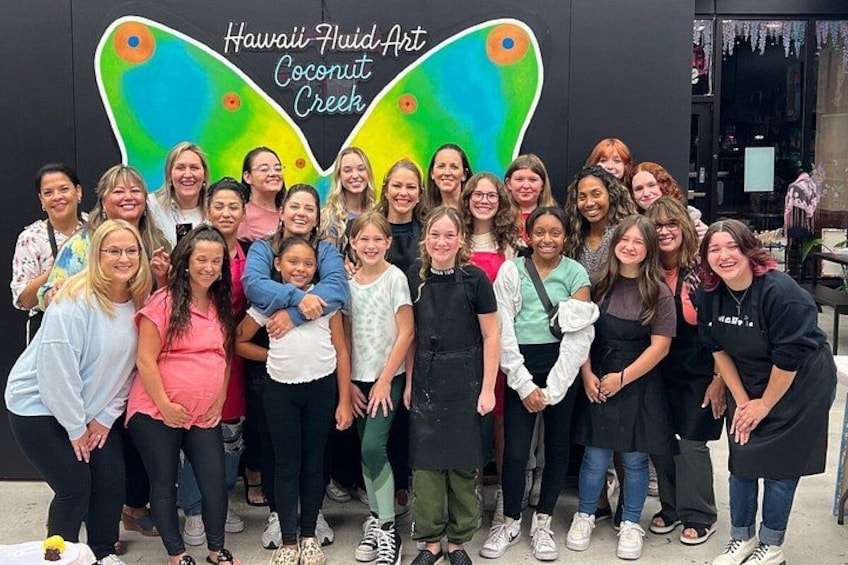 A group of people posing in front of a colorful butterfly-shaped wall with text. 4
