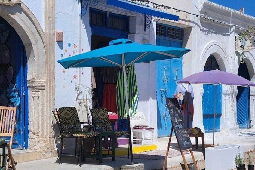 A street with blue doors and windows, outdoor seating, and a chalkboard sign. 5