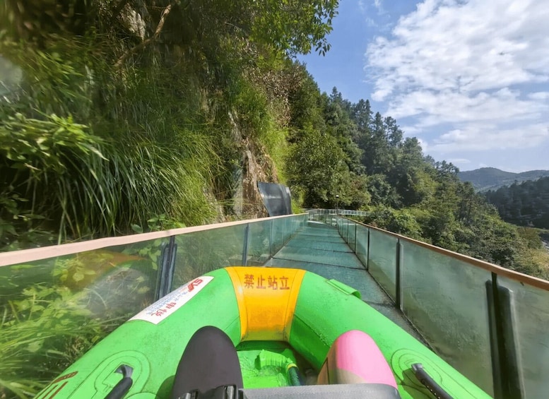 A green inflatable raft on a glass-bottomed waterway surrounded by lush greenery and hills. 4