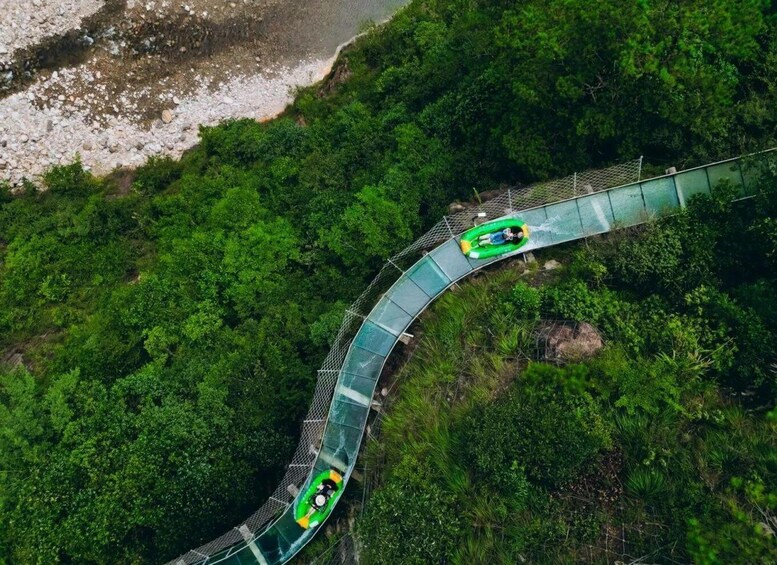 A green glass bridge curving through a forested area with a person in a green raft. 5