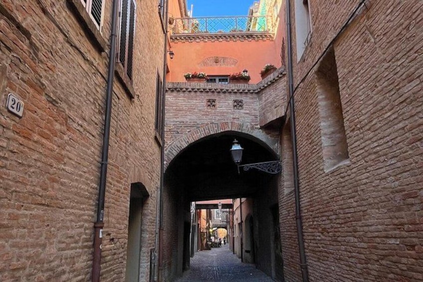 Un estrecho callejón con paredes de ladrillo, una farola y un pequeño arco. 2