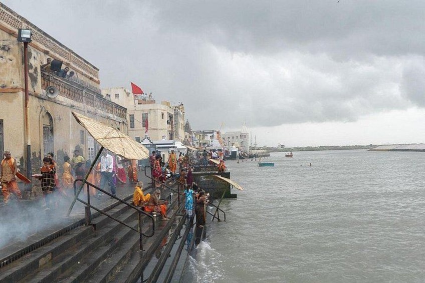 A crowded waterfront with people walking along a jetty, a boat, and buildings in the background. 5