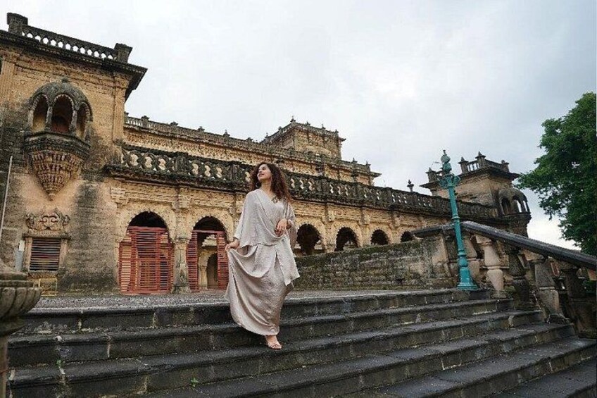 A person standing on stone steps in front of an old building with arches and a staircase. 2