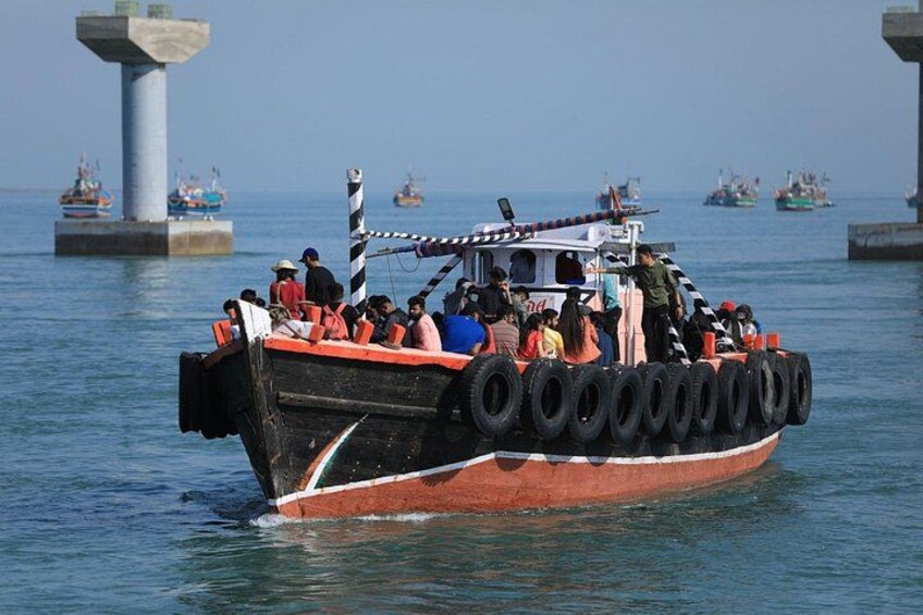 A boat with tires on its side, people on board, and other boats in the background. 1