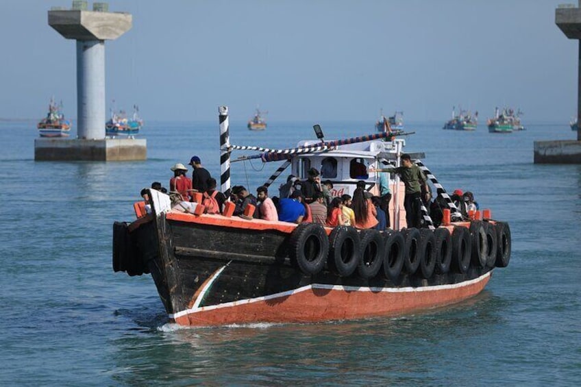 A boat with tires as outriggers, people on board, and other boats in the background. 1