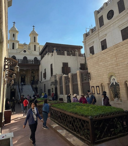 A historic plaza with people walking, a church with two towers, and a fountain. 2