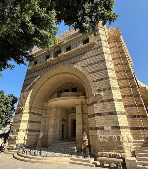 A historic building with a large arched entrance, stone facade, and steps leading up to the door. 4