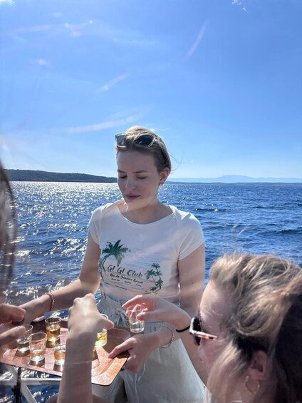 A person on a boat holding a glass, with a clear sky and calm sea in the background. 5