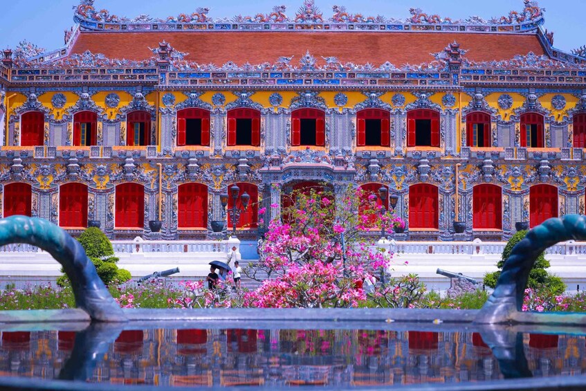 A traditional ornate building with red doors and a reflection in the water. 1