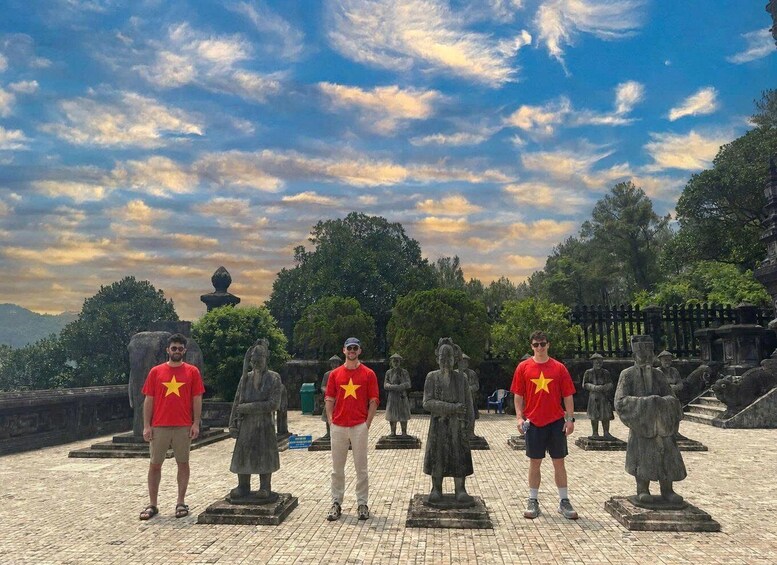 A group of people standing in front of statues in a park with a cloudy sky. 4