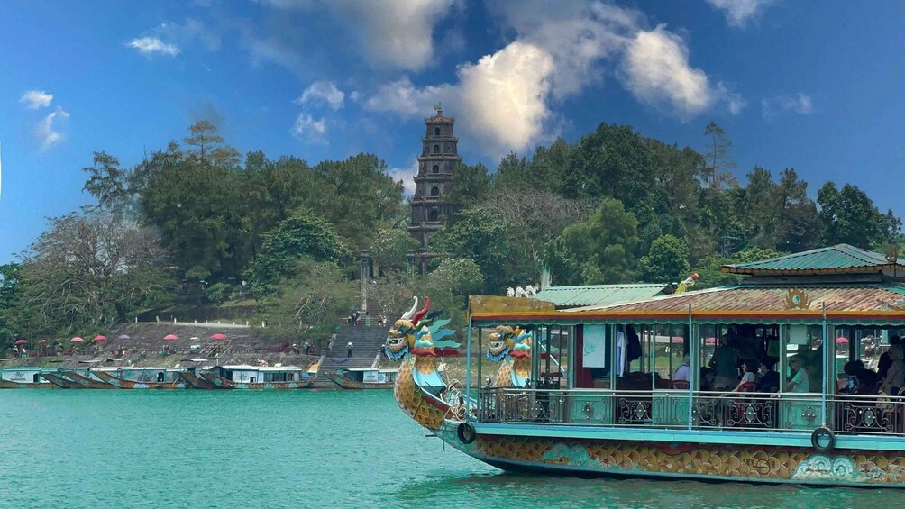 A dragon boat with passengers, a temple in the background, and a forested hill. 2