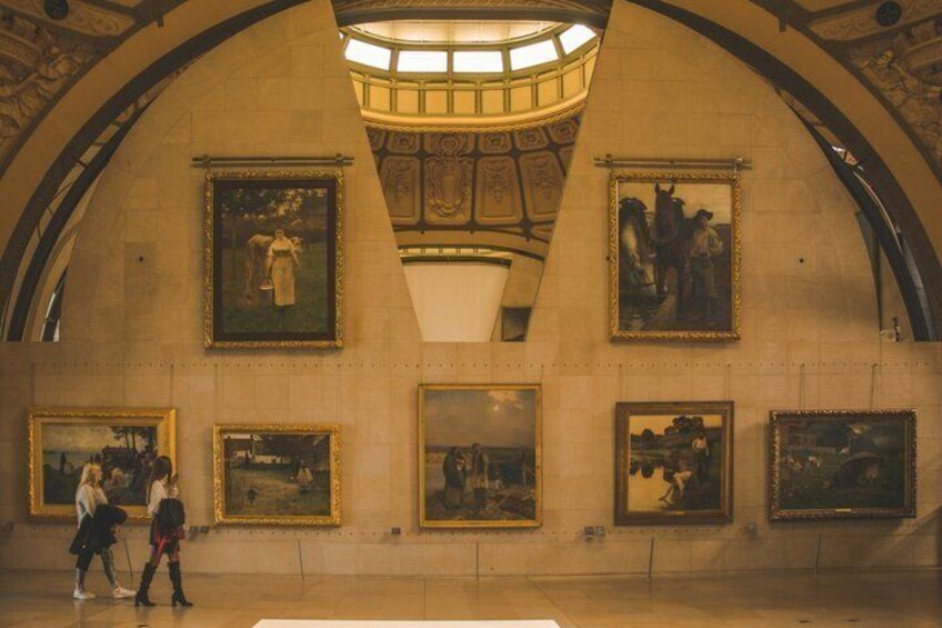 A grand hall with arched ceilings and large framed paintings on the walls. 3