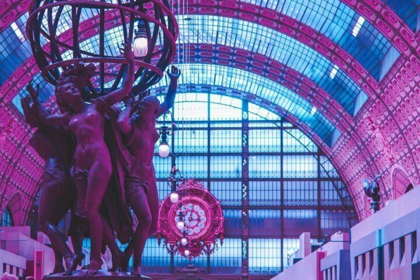 A large glass-domed structure with pink and blue lighting, a central circular decoration, and a statue of figures. 4