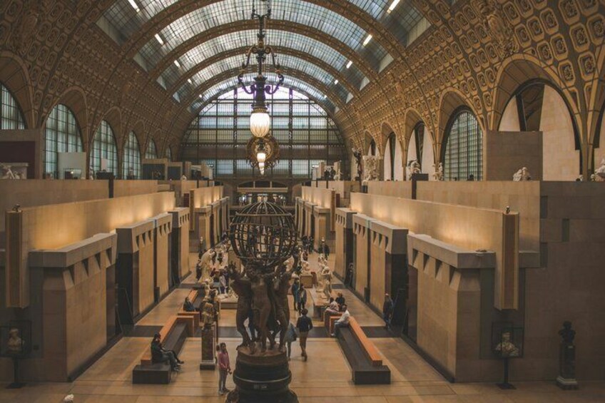 A grand hall with a high arched ceiling, large windows, and a central statue. 2