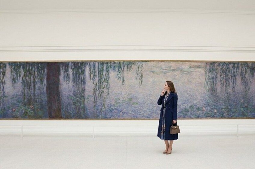 Une personne se tient dans une galerie, devant un grand tableau impressionniste représentant une forêt en arrière-plan. 5