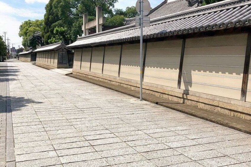 A traditional Japanese building with a tiled roof and a long, low wall. 2