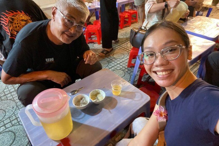 A person seated at a table with a drink and bowls of food. 2