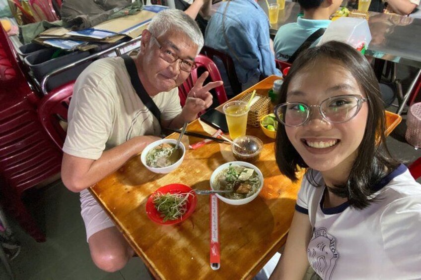 A dining table with food, a person sitting, and another person standing. 3