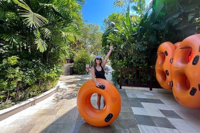A person with an orange inflatable ring, surrounded by greenery and a tiled pathway. 1