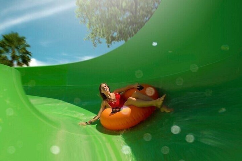 A person in a red shirt sliding down a green slide. 5