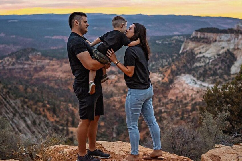 Una pareja se abraza con un niño en un afloramiento rocoso con vistas a un cañón. 4