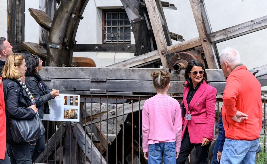 A group of people observing a historical water wheel structure. 3