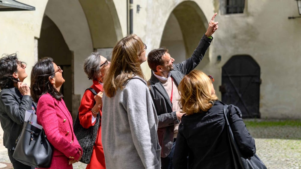 A group of people standing in an outdoor area with arches in the background. 4