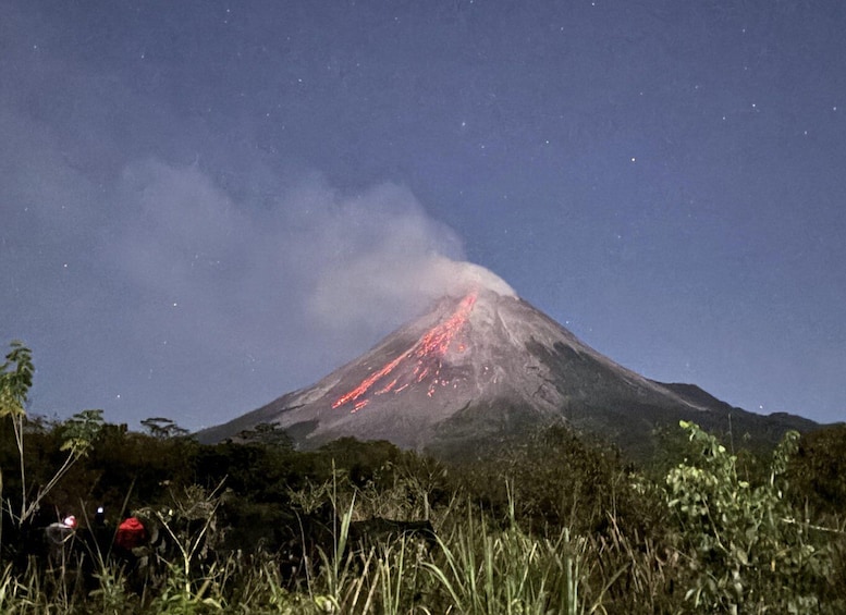 A volcano with lava flowing down its side at night. 5