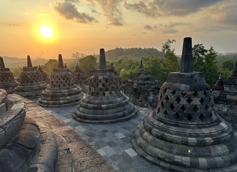 Stone stupas with intricate carvings in a temple complex during sunset. 1