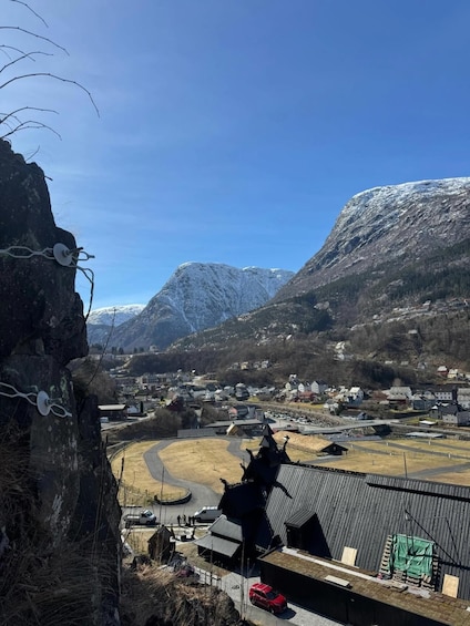 A mountainous landscape with a village, a church, and a large rock with cables. 4