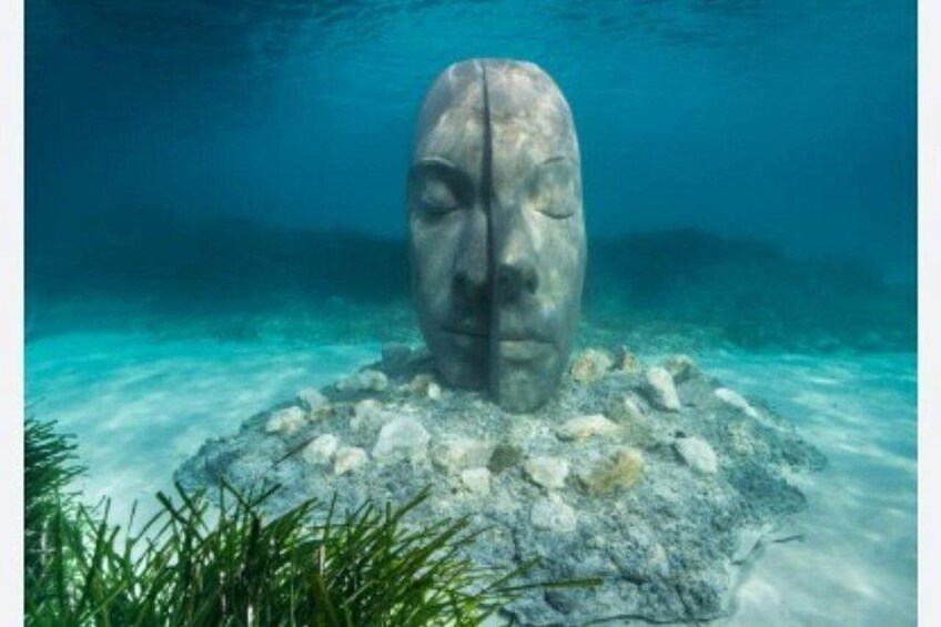 An underwater sculpture surrounded by rocks and aquatic plants. 3