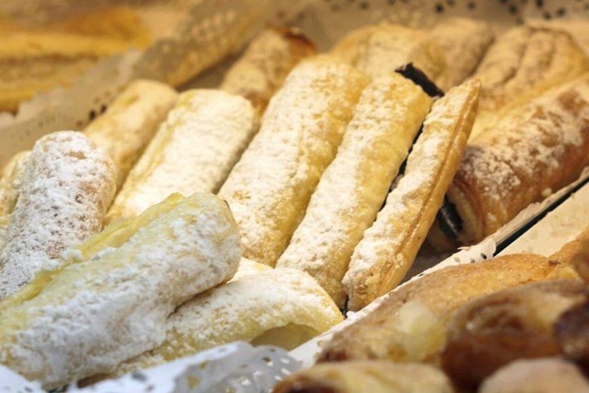 Un assortimento di pasticceria, tra cui éclair e altri dolci farciti, spolverati di zucchero a velo. 2
