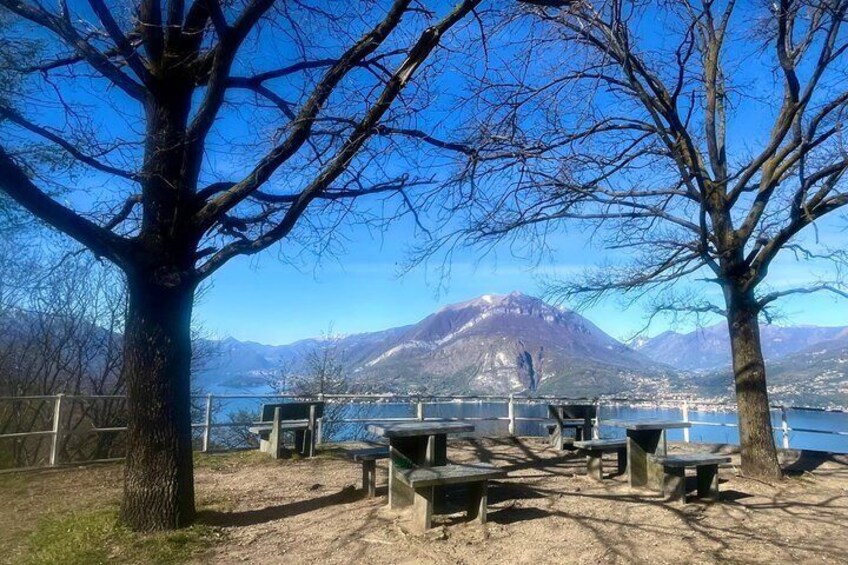 A lakeside picnic area with benches and a mountain in the background. 3