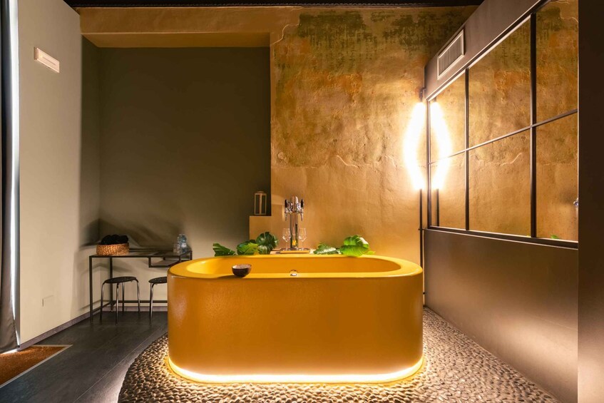 A modern bathroom with a large bathtub, a mirror, and a textured wall. 5