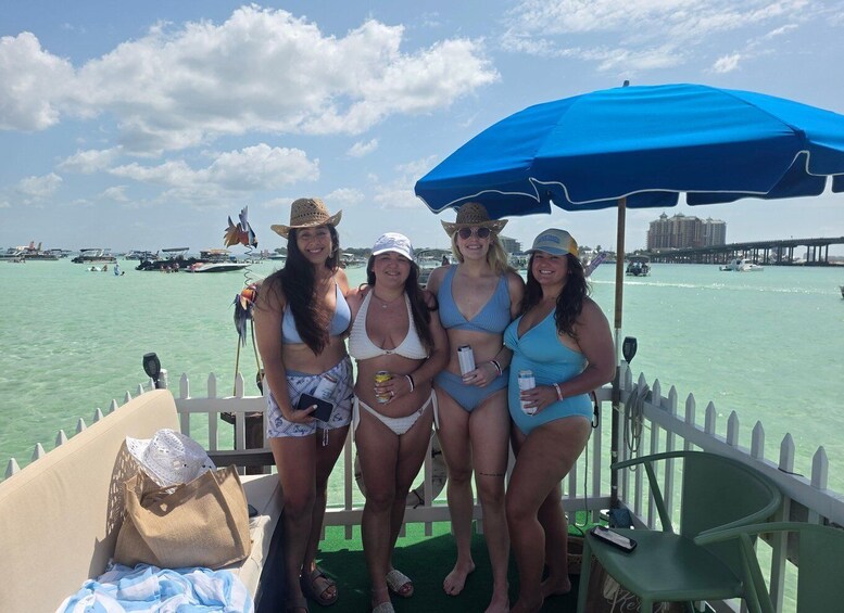 A group of people on a boat with a blue umbrella, a white fence, and a marina with boats in the background. 2