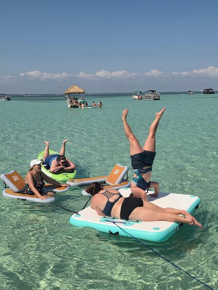 People floating on water with boats and a thatched structure in the background. 4
