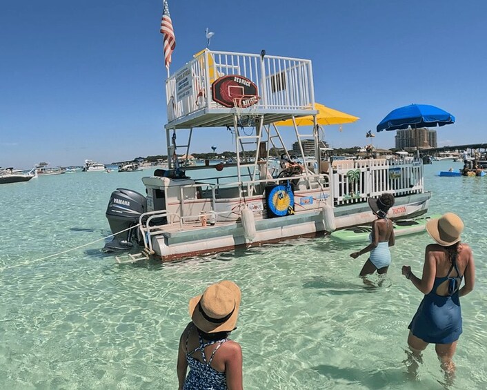 A boat with a basketball hoop, people in swimwear, and a clear blue sky. 2
