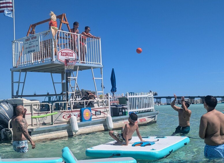 A lifeguard tower with a basketball hoop, people playing basketball, and a pier in the background. 1
