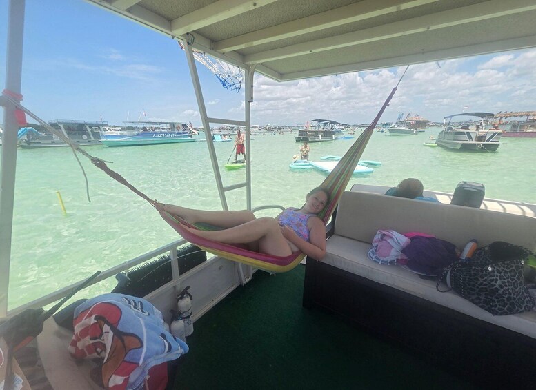 A person relaxing in a hammock on a boat, with a view of the water and other boats. 4