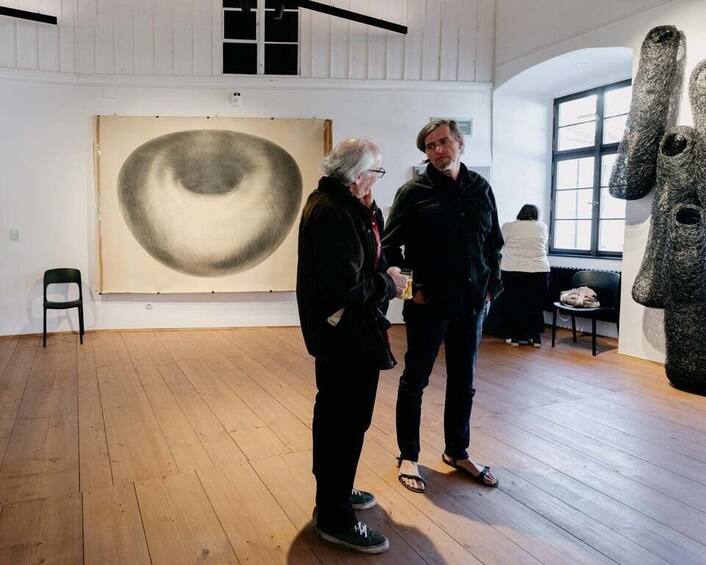 Two people in an art gallery with a large abstract painting and sculptures. 4