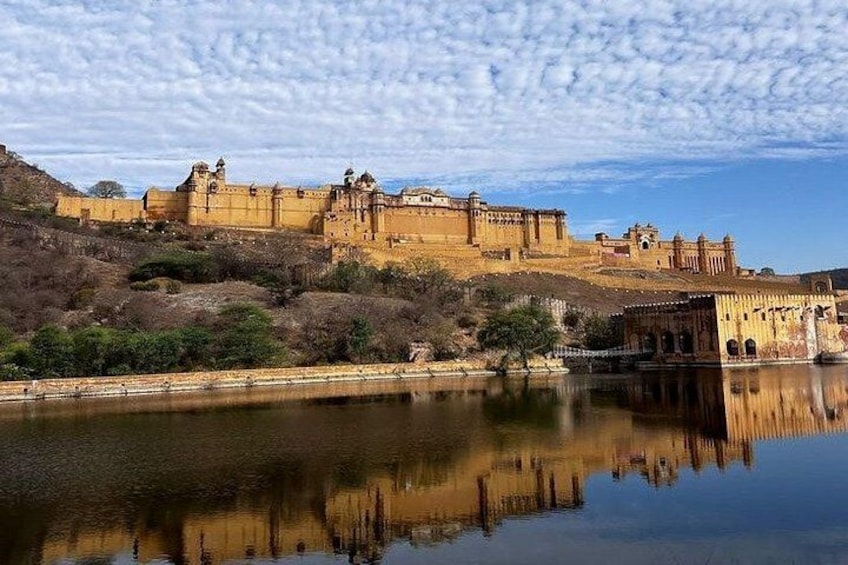 A historic fort with a reflection in the water, surrounded by hills and sparse vegetation. 2