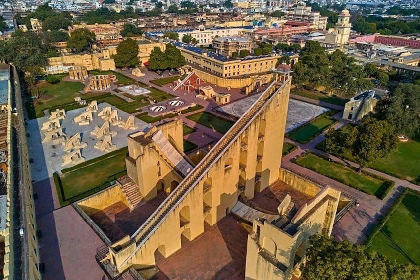 A large historical building with a prominent tower, surrounded by well-maintained gardens and smaller structures. 5