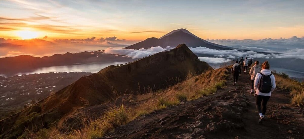 A group of hikers on a mountain trail with a volcano in the background. 3